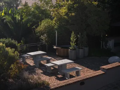 a picnic table and benches in a garden at Avemore Olive Apartment - full Backup power in Stellenbosch