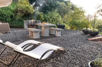 a patio with a bench and a table and a fire place at Avemore Hidden Haven - wood fired hot tub and full Backup power in Stellenbosch