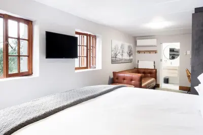 a bedroom with a bed and a couch at Avemore Hidden Haven - wood fired hot tub and full Backup power in Stellenbosch