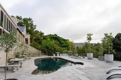 a swimming pool with benches and a patio with at Avemore Hidden Haven - wood fired hot tub and full Backup power in Stellenbosch