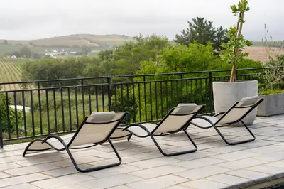 three chairs sitting on a patio with a fence at Avemore Hidden Haven - wood fired hot tub and full Backup power in Stellenbosch