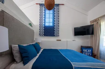 a bedroom with a blue bed and a tv at The Earthy Inn in Greyton