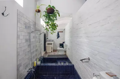 a bathroom with a toilet and a blue tile floor at The Earthy Inn in Greyton