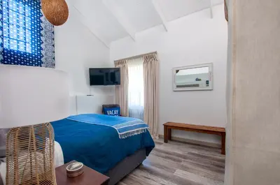 a bedroom with a blue bed and a television at The Earthy Inn in Greyton
