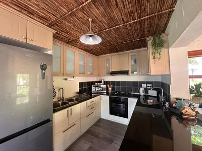 a kitchen with white cabinets and a wooden ceiling at Cottage K'Gari in Franschhoek