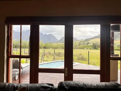a living room with a view of a pool through a window at Cottage K'Gari in Franschhoek