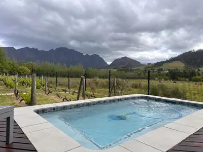 a swimming pool with a view of a vineyard at Cottage K'Gari in Franschhoek