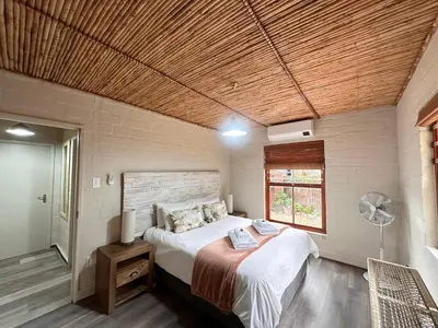 a bedroom with a bed and a window and a fan at Cottage K'Gari in Franschhoek