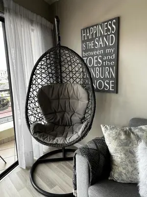 a hanging chair in a living room next to a window at Beachside Bliss Strand in Strand
