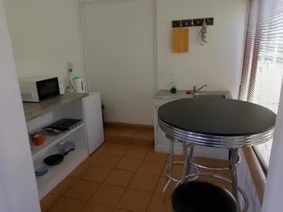 a small kitchen with a table and a microwave at Fisherhaven Guest House in Hermanus