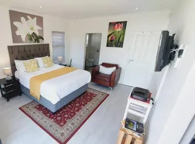 a bedroom with a king sized bed and a chair at Cosy Nest - Uncapped Wi-fi & Self Check-in in Cape Town