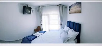 a bedroom with a white bed with a window at Blue Nile Guest in Cape Town