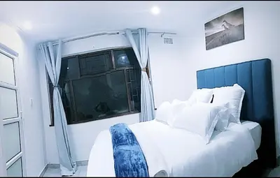 a bedroom with a large white bed with a window at Blue Nile Guest in Cape Town