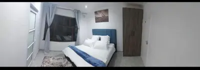 a bedroom with a bed with white sheets and a window at Blue Nile Guest in Cape Town