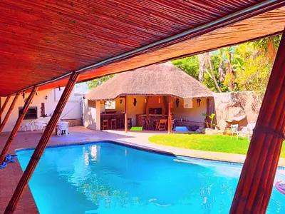 a house with a swimming pool with a thatch roof at Durbanville Pool House in Durbanville