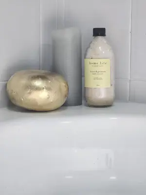 a bottle of soap next to a potato and a candle at Durbanville Pool House in Durbanville