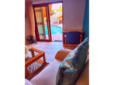 a living room with a couch and a table at Durbanville Pool House in Durbanville