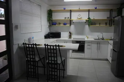 a kitchen with two bar stools at a counter at Nature's Rest in Cape Town