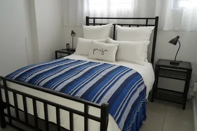 a bed with a blue and white striped blanket and pillows at Nature's Rest in Cape Town