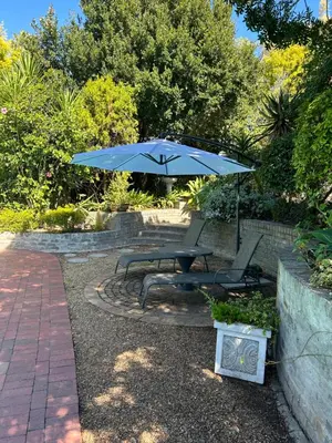 a picnic table with a blue umbrella and chairs at Garden View Inn in Cape Town