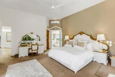 a bedroom with a large white bed and a desk at Erinvale Luxury Villa in Cape Town