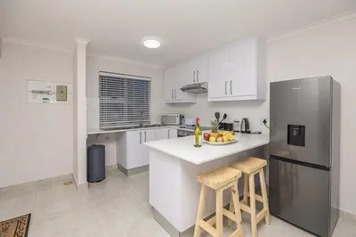 a kitchen with white cabinets and a stainless steel refrigerator at Blouberg Pearl in Cape Town
