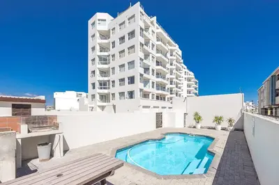 a apartment with a swimming pool and a building at Blouberg Pearl in Cape Town