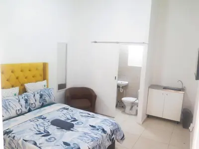 a bedroom with a bed and a chair and a bathroom at lodgeon91 in Cape Town