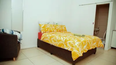 a bedroom with a bed with a yellow and orange blanket at lodgeon91 in Cape Town
