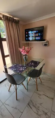 a dining room with a glass table and two chairs at Cozy Batchelor Labiance in Cape Town
