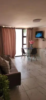 a living room with a couch and a glass table at Cozy Batchelor Labiance in Cape Town
