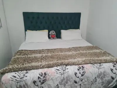 a teddy bear sitting on top of a bed at Elikem Properties in Cape Town