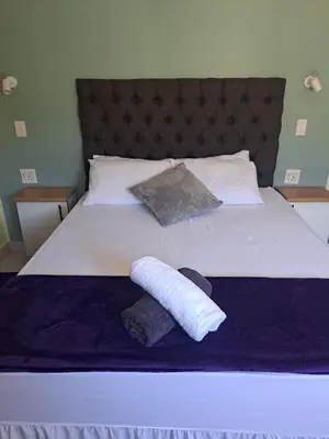 a bed with two pillows and two towels on it at Olivia's guest house in Cape Town