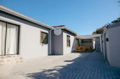 a white house with a brick driveway at Lovely and Peaceful 3 bedroom house in Cape Town