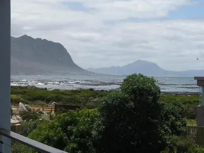a view of the ocean with mountains in the background at Whalers Retreat in Bettyʼs Bay