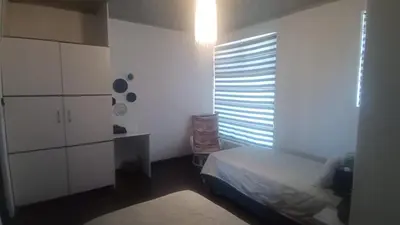 a bedroom with a bed and a dresser and a window at Whalers Retreat in Bettyʼs Bay