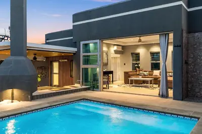 a swimming pool in front of a house at Rancho Relaxo in Bloubergstrand