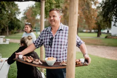 a man holding a tray of food on a table at Heins Manor House in Stellenbosch