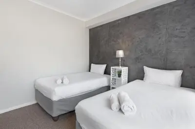 a room with two beds and a chair in it at Waterstone East C103 by Host Agents in Cape Town