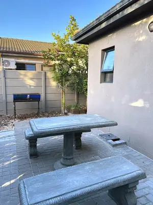 a picnic table with two benches in front of a building at 81 on Groenewoud in Cape Town