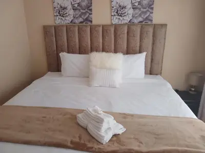 a pile of white towels sitting on a bed at Elim Rest Place in Fisherhaven