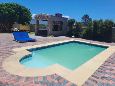 a swimming pool with two blue chairs and a house at Elim Rest Place in Fisherhaven
