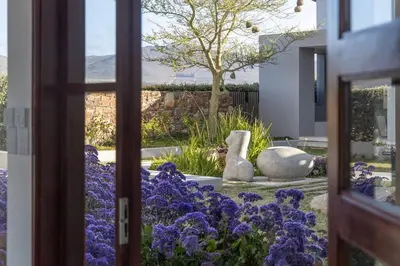 a window view of a garden with purple flowers at Benguela Cove - Oceans Away in Hermanus