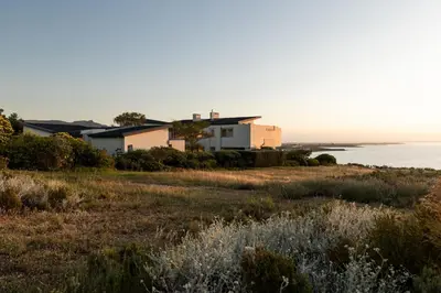 a house on a hill with the ocean in the background at Benguela Cove - Oceans Away in Hermanus