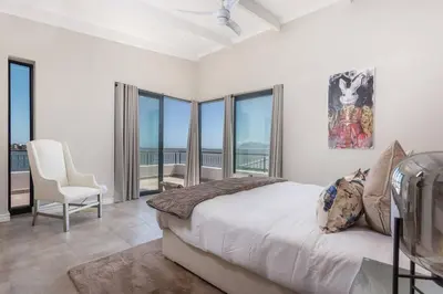 a bedroom with a bed and views of the ocean at Benguela Cove - Coastal Retreat in Hermanus