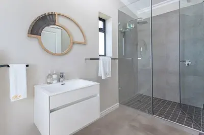 a bathroom with a shower and a sink and a mirror at Benguela Cove - Coastal Retreat in Hermanus