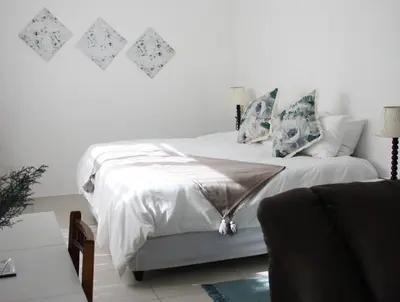 a bedroom with a bed with white sheets and pillows at Eucalyptus Cottage in Cape Town