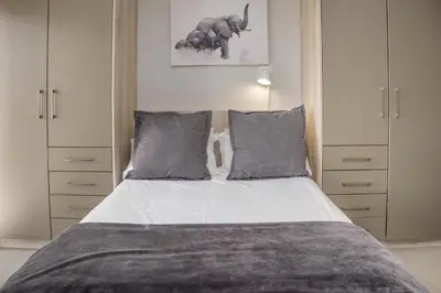a bedroom with a large bed with gray pillows at Stylish Studio Stellenbosch - Airconditioned in Stellenbosch