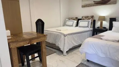 a room with two beds and a desk and a table at MELJAA STAR Guesthouse in Cape Town