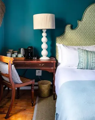 a bedroom with a bed and a table with a lamp at The Belmont in Franschhoek